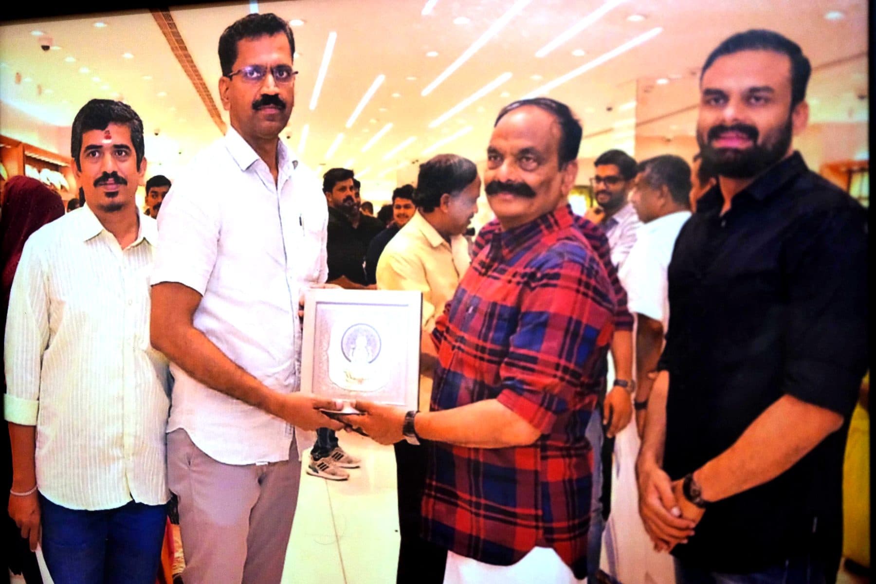 Felicitation moment, presenting a framed silver Lakshmi artwork at a jewellery house