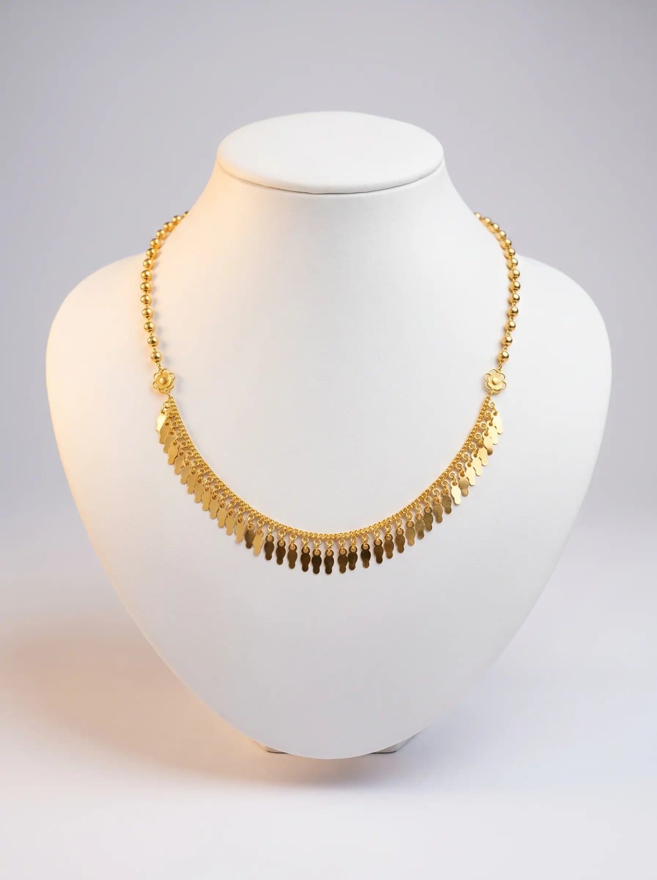 Hand-finished gold leaf-fringe necklace on a white display bust